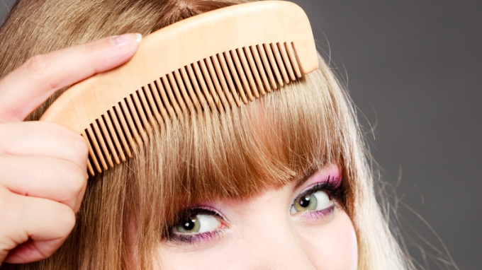 Closeup woman combing her fringe with comb