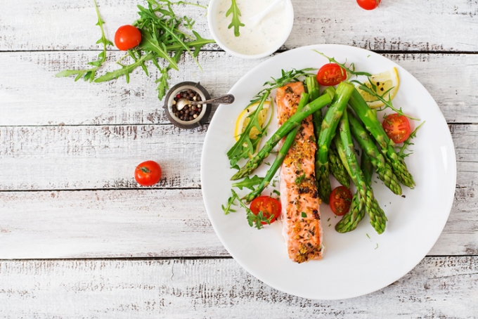 Baked salmon garnished with asparagus and tomatoes with herbs
