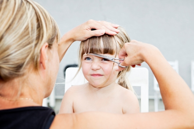 Woman cutting young girls hair